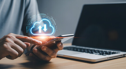 Person using smartphone with glowing cloud icon and laptop on desk