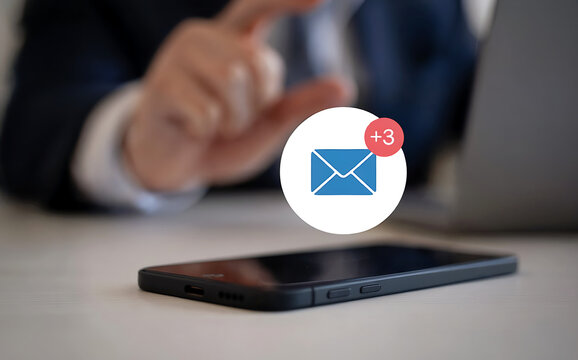 A smartphone displays an email notification with a red badge indicating unread messages, while a persons hand gestures in the background