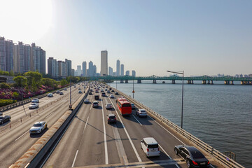 Aerial View of Olympic-daero Highway alongside Han River with Hangang Bridge and Iconic 63 Building in Seoul Cityscape under Clear Blue Sky