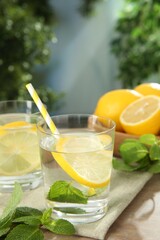 Fototapeta premium Refreshing water with lemons and mint on wooden table outdoors, closeup