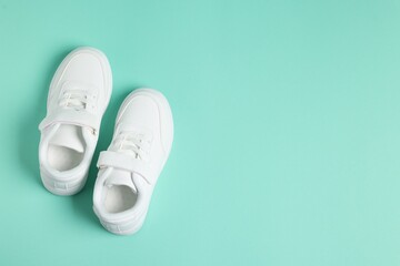 Pair of kid's sneakers on turquoise background, top view with space for text. Stylish shoes