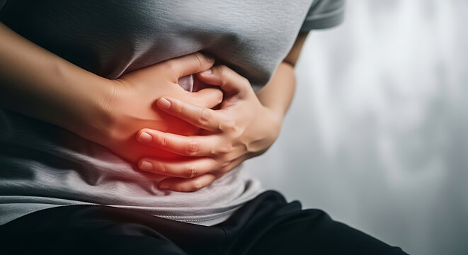 Person holds their stomach in pain, indicating abdominal discomfort and digestive issues.