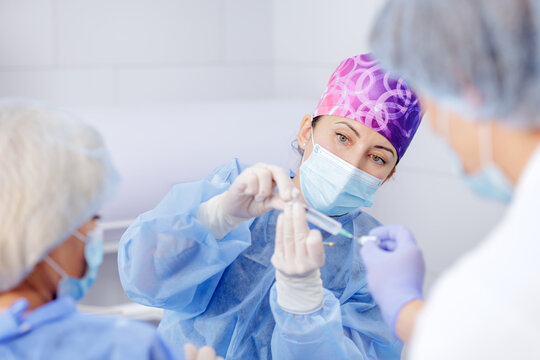 Female surgeon preparing syringe injection for patient in modern hospital operating room - Powered by Adobe