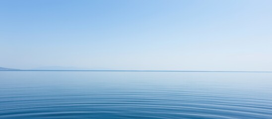 Serene blue ocean with gentle ripples under a clear sky.