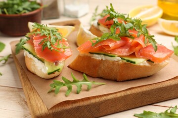 Tasty bruschettas with salmon and cream cheese served on wooden table, closeup