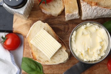 Slices of baguette with butter, basil, tomatoes and knife on light table, flat lay