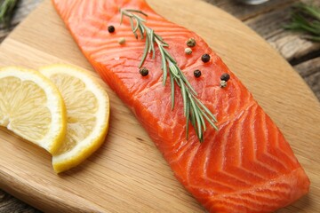 Piece of salmon fillet, spices and lemon on wooden table, closeup