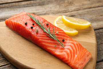 Piece of salmon fillet, spices and lemon on wooden table, closeup