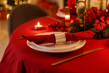 Stylish Christmas table setting with plates, festive decor and burning candles indoors, closeup