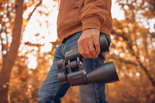 Amateur birdwatcher observing birds and other animals in nature with binoculars.