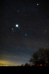 Milky Way stars and rural countryside tree silhouettes.