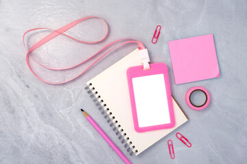 Pink plastic badge with book and stationery on white stone texture background. Template designed for employees of company