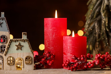 Burning candles and Christmas decor on wooden table against dark background with blurred lights, closeup. Bokeh effect