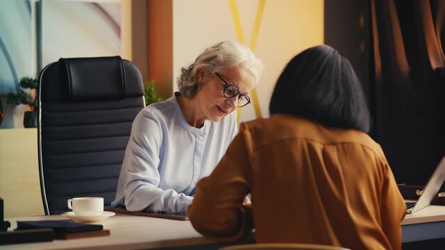 HR manager in her 50s interviewing female candidate for job, reading her CV