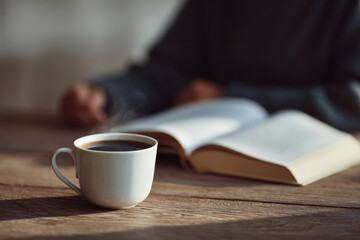 steaming cup of coffee sits on wooden table next to open notebook and blurred white text bars interface