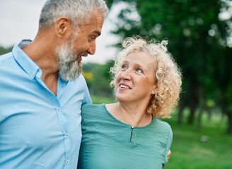 Portrait of a happy middle aged woman and  active middle aged white couple having fun walking holding hands and bonding in park outdoors