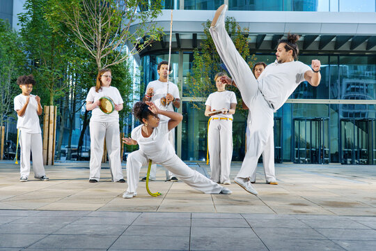 A group of sporty people of different ages training capoeira in a big city