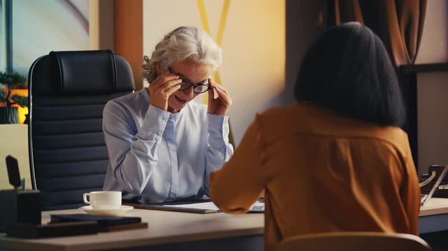 Woman recruiter in her 50s reviewing CV of female candidate during job interview