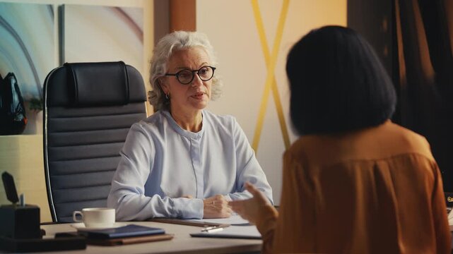 Female job candidate showing CV to senior woman HR manager during interview