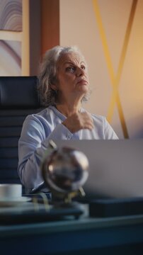 Female boss in her 50s feeling hot flash while working in office, menopause sign