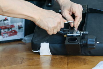 Hands adjusting spring mechanism with wrench on black chair base. Close-up of hands using adjustable wrench to tighten spring mechanism on black office chair base assembly