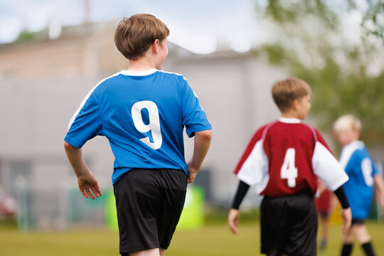 Kids in Blue and Red Jerseys on Soccer Field. Youth Soccer Match in Action. Kids Competing on the Field Wearing Blue and Red Team Jerseys during Football Practice