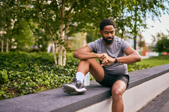 Determined Man Takes a Break After Workout in Park While Planning Weight Loss Journey - Powered by Adobe