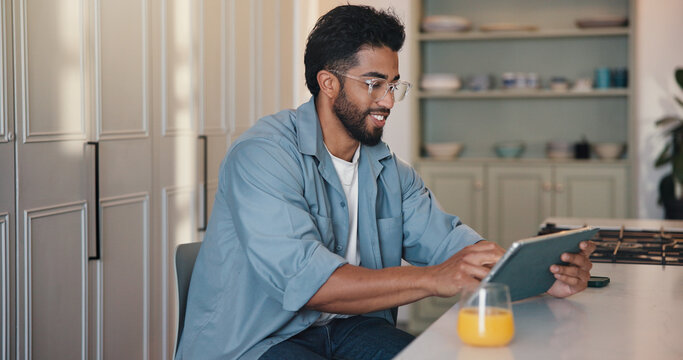 Remote work, smile and tablet with man in kitchen of home for startup planning or research. App, reading and small business with happy freelance employee at counter in apartment for email feedback - Powered by Adobe
