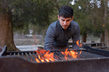 Man preparing barbecue grill with burning charcoal outdoors