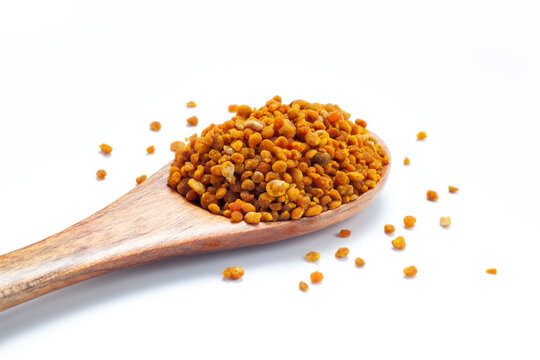 bee pollen grains in wooden spoon isolated on white background