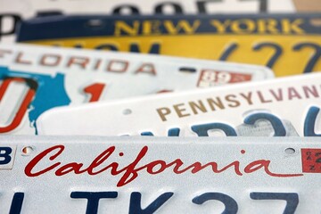 Old US car license plates with various state names close up. Concept of driving in United States. Reaching a car registration