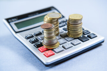 Gray calculator and coins on a blue background.
