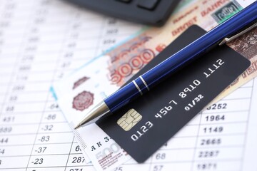 Credit card and pen with russian ruble currency money bills banknotes on calculations document background. Business, financial operations and accounting in Russian Federation