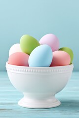 Fototapeta premium Colorful pastel Easter eggs arranged in a white ceramic bowl on light blue wooden surface with soft background, symbolizing spring celebration, festivity, and seasonal decoration