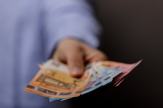 Person hand holding out euro banknotes symbolizing payment finance earnings profit investment and business concepts - Powered by Adobe