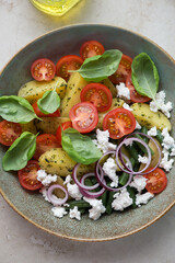 Salad with potato wedges, cherry tomatoes, green beans and ricotta in a rustic plate, middle close-up, vertical shot, elevated view