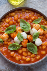Italian chicche di patate in tomato sauce with mozzarella balls and basil, vertical shot, middle close-up