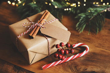 Brown Christmas gift box with a blank tag on rustic wooden table.