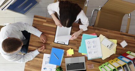 Man manager gives clipboard with contract agreement to female partner in boardroom. Business colleagues deal with formal papers in office at meeting - Powered by Adobe