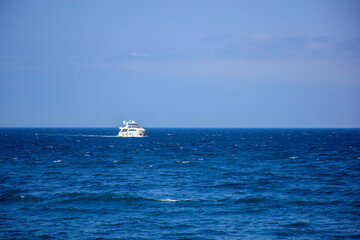 White luxury yacht sailing on the sea, view from afar of the open space of the sea