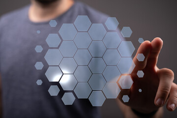 A person's finger touching a virtual hexagonal pattern representing future technology, innovation and digital c