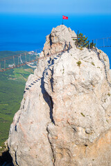 A suspension rope bridge on a high cliff over an abyss with the sea in the background. Extreme Tourist Attraction in the Mountains