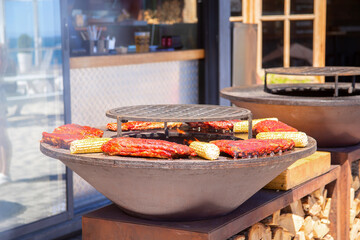 A piece of meat and ears of corn are grilled. Barbecue outside in a local cafe on an open fire