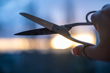 hand holding vintage Rusty old scissors against sunset, symbolizing endings, change, and creativity. Artistic concept, symbolizing decisions, endings, and new beginnings. Conceptual photography