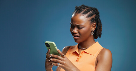 Fototapeta na wymiar Confused, phone and text message with black woman in studio for fraud or phishing scam reaction. App, doubt and typing with African person on blue background for contact or fake news notification