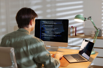 Programmer working on computer at table in office, back view