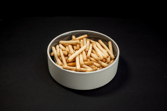 Small breadsticks on white plate on black background - Powered by Adobe