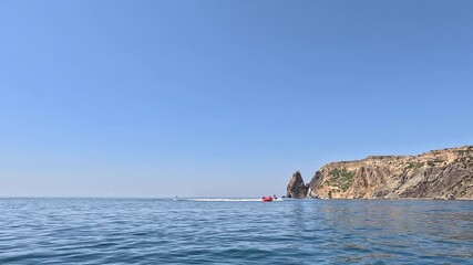 Sea water sports, jet skis, banana boat ride near beautiful rocky cliffs. - Powered by Adobe