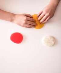 Hands stretching soft glossy slime under light. Expresses color, texture, and imagination.
