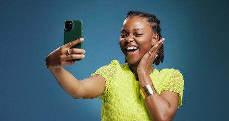 Selfie, smile and social media with black woman in studio for profile picture or status update. App, excited and photograph with African content creator on blue background for streaming platform